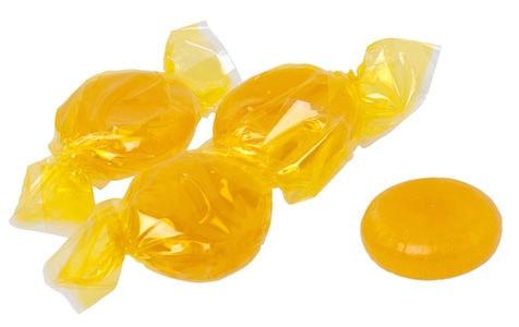 Four golden butterscotch candies, with three wrapped in plastic, and one unwrapped.