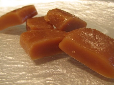 Five caramels resting upon one another atop a foil surface.